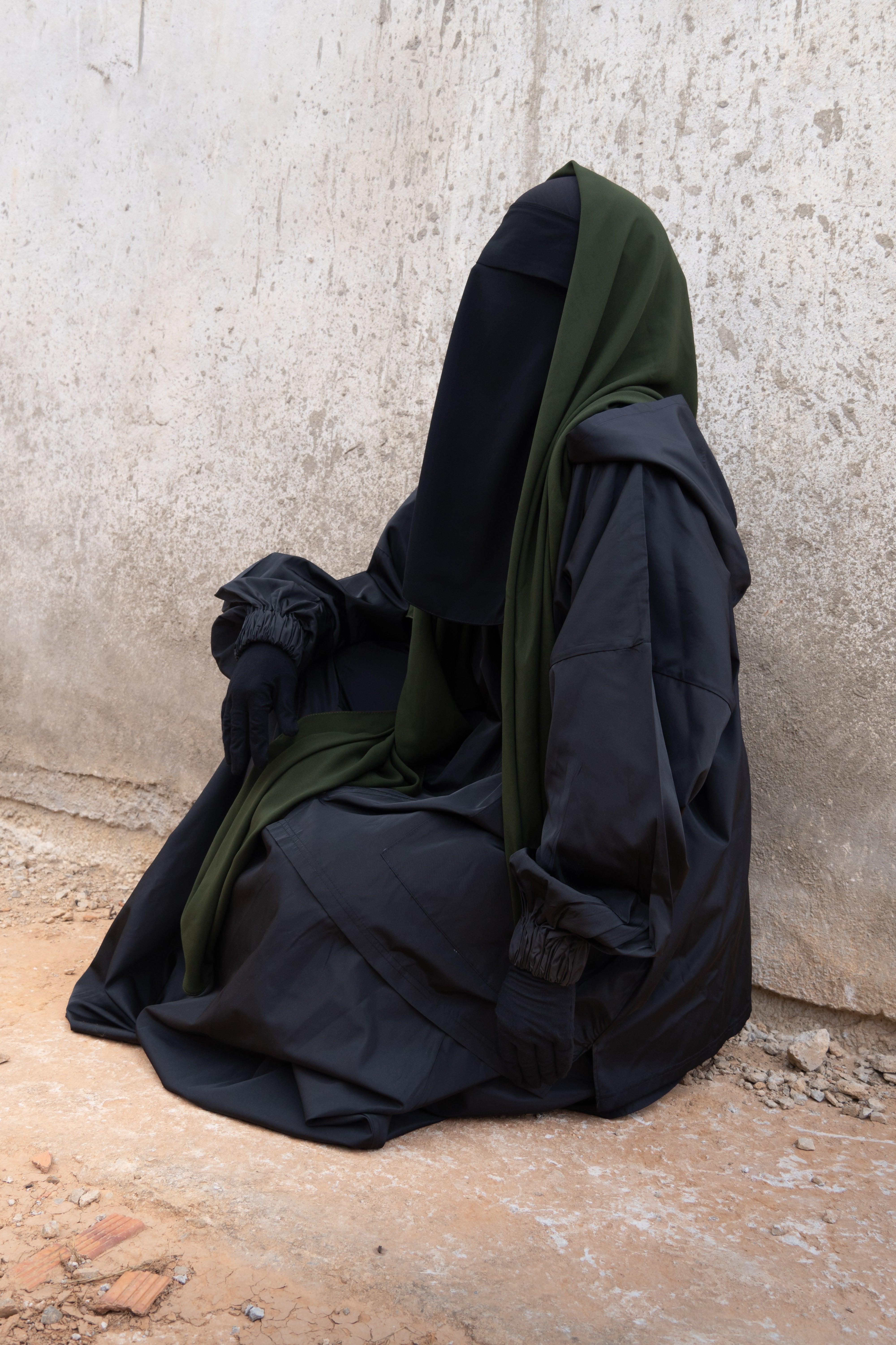 Femme musulmane assise portant une parka noire légiférée de la marque hijrati  